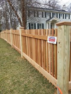 a wooden fence with a sign on it that says capital fence in front of a house