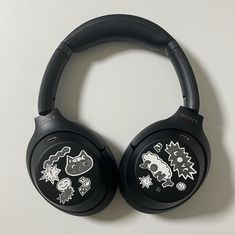 two black headphones with stickers on them sitting next to each other in front of a white wall