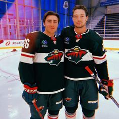 two men standing next to each other on top of an ice rink wearing hockey uniforms