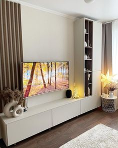 a flat screen tv sitting on top of a white entertainment center in a living room