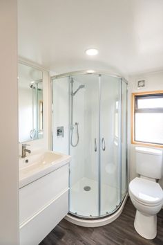 a bathroom with a toilet, sink and shower in it's corner stall next to a window