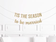 a white couch sitting under a banner that says tis the season to be married on it