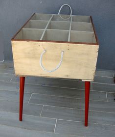 a wooden box with rope hanging from it's sides on top of a red stand