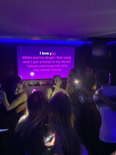 a group of people standing in front of a projection screen with the words i love you written on it