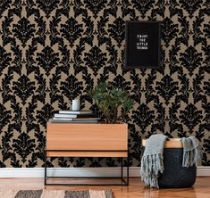 a black and gold damask wallpaper in a living room with a plant on the end table