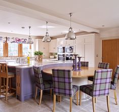 a kitchen filled with lots of counter top space and wooden dining table surrounded by chairs