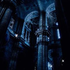 the interior of an old church with columns and stained glass windows, lit up at night