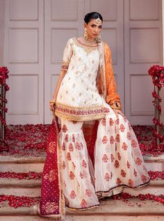 Embrace the essence of tradition and elegance with our stunning Chunri chiffon off-white ensemble, adorned with intricate machine work and heavy hand embroidery on the neck, hem, and sleeves. Paired perfectly with an organza embroidered gharara, accentuated with light handwork and scattered chan, creating a harmonious blend of texture and elegance. The look is completed with a gradient organza dye block print dupatta, embellished with sequin and gota spray and the finishing of jamwar and kiran a Designer White Raw Silk Palazzo Set, White Raw Silk Palazzo Set For Designer Wear, Off White Georgette Palazzo Set With Dupatta, White Bollywood Style Raw Silk Palazzo Set, Festive White Raw Silk Palazzo Set, Semi-stitched Off White Palazzo Set With Intricate Embroidery, White Chinon Palazzo Set With Dupatta, Off White Palazzo Set With Intricate Embroidery For Eid, White Palazzo Set With Dupatta For Reception