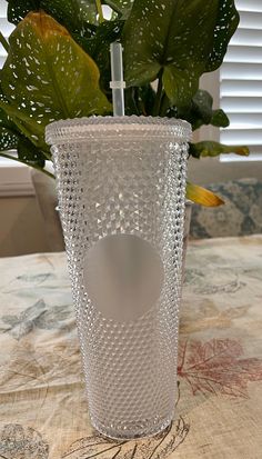 a glass vase with a plant in it sitting on a table next to a window