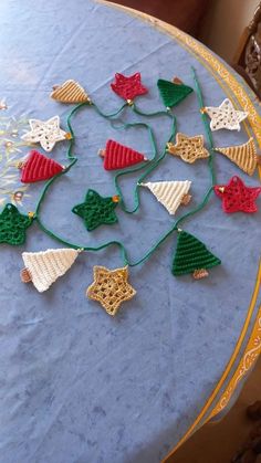 crocheted christmas decorations are arranged on a blue tablecloth with gold trimmings