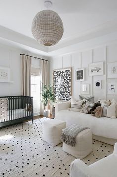 a living room filled with white furniture and lots of pictures on the wall next to a baby crib