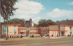 motels on the corner of an empty street with cars parked in front and behind them