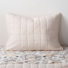 a white pillow sitting on top of a bed next to a wall with a clock