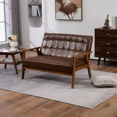 a brown leather couch sitting on top of a wooden floor next to a white rug