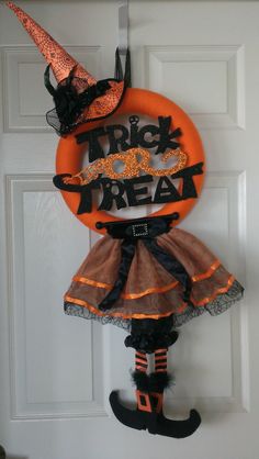 a door hanger decorated with an orange and black trick or treat wreath on it