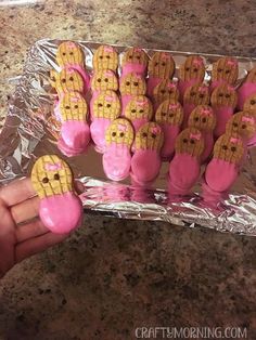 someone is holding up some cookies in the shape of corn on top of pink icing