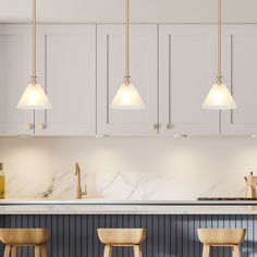 three pendant lights hang over a kitchen island with stools and countertop in front of it