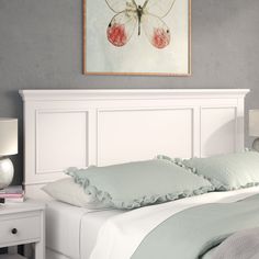 a bed with white headboard and pillows on top of it next to a night stand