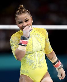 a woman in a yellow bodysuit wiping her teeth