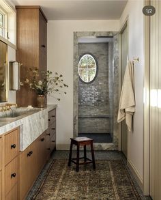 a bathroom with a round window in the wall and rug on the floor next to it