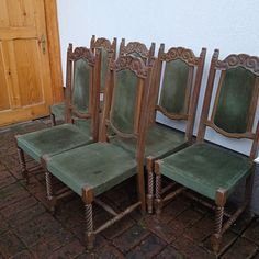 four green chairs sitting next to each other in front of a white wall and door