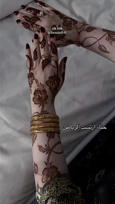 a woman's hands with hennap and bracelets on her arm, in arabic script