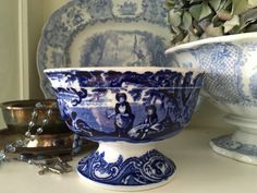 a blue and white bowl sitting on top of a table next to other dishes with flowers in the background