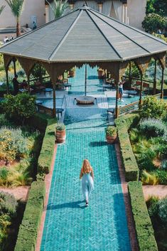 a woman walking down a path in front of a gazebo