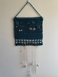 a crocheted wall hanging with beads and chains attached to the side of it