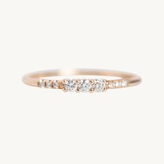 a gold ring with three diamonds on the top and bottom, set in 18k rose gold