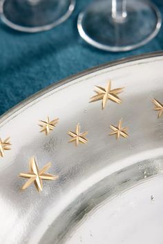 four gold stars on a silver plate next to wine glasses and a blue table cloth