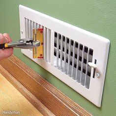 a person is using a pair of pliers to cut the side of a wall heater