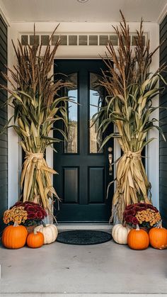 two pumpkins are sitting on the front porch with corn stalks and gourds