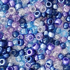 blue and purple glass beads are shown in close up on a white tablecloth with silver sequins