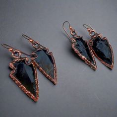 These Obsidian Arrowhead Earrings are an original design by Marie, handmade in Santa Fe, NM. FEATURES: * beautiful boho style drop earrings * feature obsidian arrowheads * electroformed copper edges * Niobium ear wires - niobium is naturally hypo-allergenic, making it especially suited for those with metal sensitivities * antique copper finish THE STONE: OBSIDIAN - root chakra  * spiritual communication  * protection  * cleanser of psychic smog  * grounding  * release of resentment, fear and anger  DETAILS * handmade to order by me in my studio in Santa Fe, NM * ready to ship in 3 - 5 business days in an eco-friendly jewelry gift box using recyclable packaging. All items are ready for gift giving. * due to hygiene reasons earrings are non returnable/nonrefundable, but please contact me if Handmade Black Arrowhead Jewelry, Artisan Black Earrings As Gift, Artisan Black Earrings Gift, Artisan Black Earrings For Gift, Artisan Black Jewelry With Ear Wire, Handmade Arrowhead Jewelry Gift, Handmade Black Copper Earrings, Electroformed Earrings, Arrowhead Jewelry