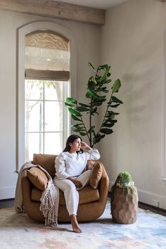 a woman sitting in a chair next to a potted plant