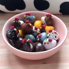 a pink bowl filled with lots of different colored candies on top of a wooden table