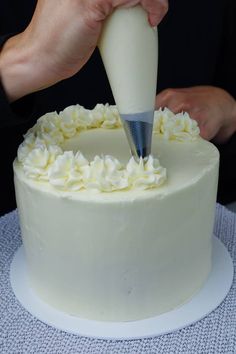 a person is decorating a white cake with icing and a small knife on top