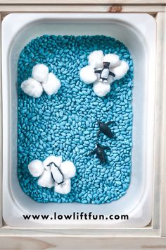 a blue and white tray filled with cotton balls, black plastic birds and fake clouds