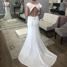 a woman in a wedding dress looking at herself in the mirror with her back to the camera