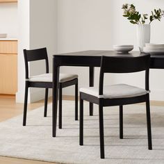 a dining room table with two chairs and a bowl on top of the table in front of it