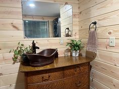 a sink and mirror in a room with wood paneling on the wall behind it