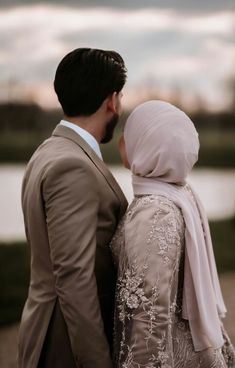 a man and woman standing next to each other in front of a body of water