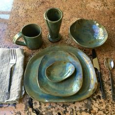 a table set with dishes and utensils on top of a granite countertop