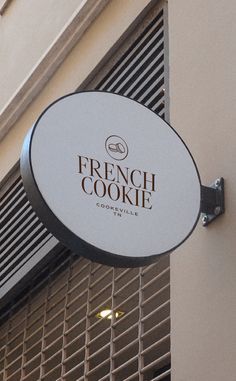 a sign hanging from the side of a building that says french cookie on it's front