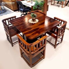 a wooden table with four chairs and a potted plant sitting on top of it