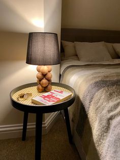 a bedroom with a bed, nightstand and lamp on the side table in front of it