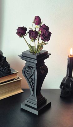 there is a vase with flowers in it on the table next to a candle and some books