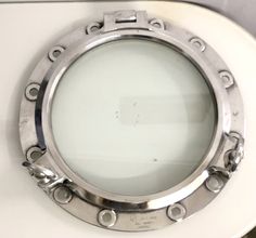 a metal porthole on the side of a white toilet seat with rivets