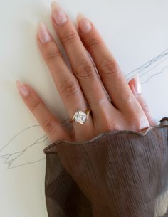 a woman's hand with a diamond ring on top of her left hand, next to a drawing